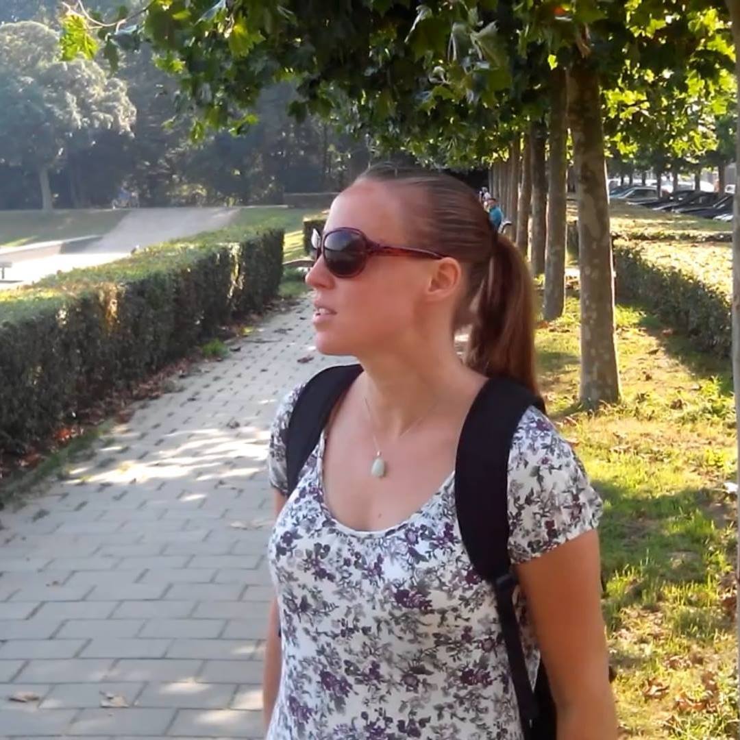 Iris van Rooijen walking in a sunlit park wearing sunglasses and a backpack